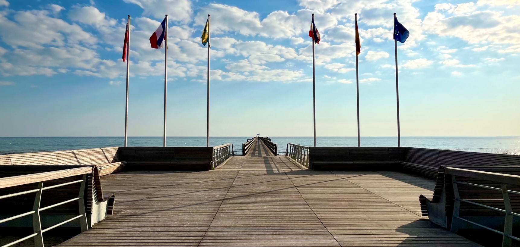 Seebrücke mit Fahnen und Blick aufs Meer