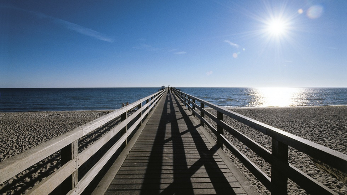 Seebrücke von vorne mit Strand und Sonenschein